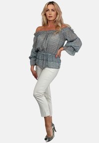 Bluzka odsłonięta na ramiona w niebiesko-białym kwiatowym wzorze, z falbanym dołem. W połączeniu z białymi spodniami 3/4 i wysokimi butami w wężowy wzór.