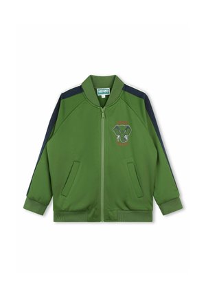 Giacca verde con cerniera e dettagli blu navy, tasche frontali, polsini a coste e grafica di elefante ricamata. Realizzata in tessuto leggero e liscio.
