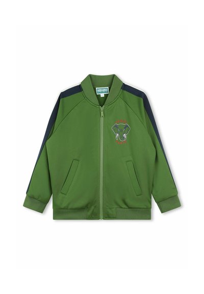Giacca verde con cerniera e dettagli blu navy, tasche frontali, polsini a coste e grafica di elefante ricamata. Realizzata in tessuto leggero e liscio.