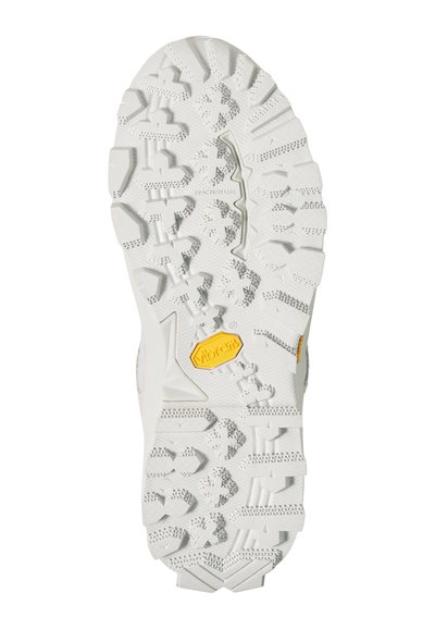 Semelle de chaussure robuste blanche avec des crampons profonds multidirectionnels et un logo Vibram jaune près du centre pour une meilleure adhérence et durabilité.