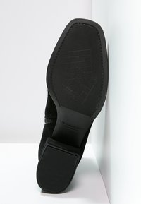 Semelle de chaussure noire avec motif de grip texturé, bout carré, talon bas, et nom de marque "Vagabond" embossé en dessous.