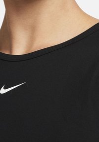 Czarna sportowa koszulka z okrągłym dekoltem, wykonana z gładkiej tkaniny. Na lewej stronie znajduje się białe logo Nike. Krótkie rękawy.
