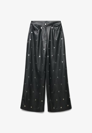 Pantalons larges en cuir noir ornés de clous circulaires métalliques répartis uniformément sur le tissu, avec un design standard à cinq poches.