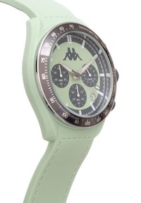 Mintgrön silikonklocka med boett i rostfritt stål. Rund urtavla med svarta underdials och silverfärgade timmarkörer. Kappa-logotypen är synlig.