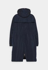 Marineblå vandtæt jakke med hætte, der har lynlås og elastisk talje. Glat tekstur og lang design. Ingen synlige mønstre.