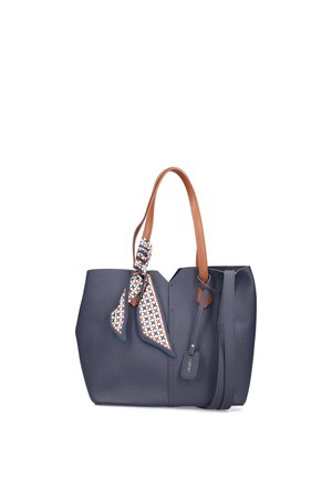 Sac à main bleu marine avec des poignées en cuir marron, un foulard à motifs noué autour d'une poignée et une étiquette bleu marine avec le nom de la marque attachée.