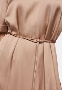 Beige dress featuring a smooth satin texture with a tied belt at the waist, short sleeves, and vertical pleats for added detail.