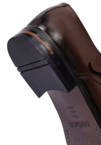 Bruine leren schoen met een ronde neus, platte zool en een contrasterende lichtbruine streep. Beschikt over een gestructureerde rubberen loopzool voor grip.