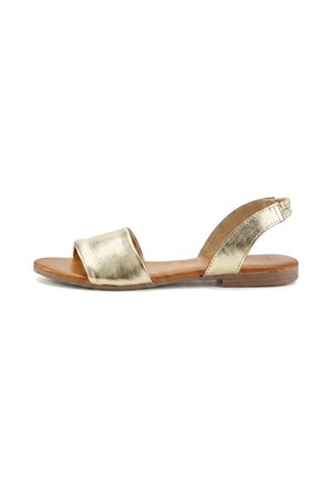 Flache Sandale mit goldfarbenem Metallriemen über den Zehen und goldfarbenem Slingback-Riemen, braune Sohle und niedriger Absatz.