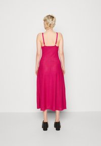 Fuchsia midiklänning med justerbara axelremmar, åtsittande bodice och utsvängd kjol, tillverkad av ett lätt tyg som har en slät yta.