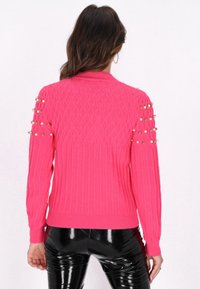 Pulover tricotat de culoare roz aprins, cu textură ribbelată, guler și mărgele decorative pe umeri. Design ajustat cu mâneci lungi.