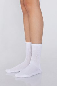 Weiße Baumwoll-Knöchelsocken mit geripptem Muster, glatter Oberfläche und verstärkter Spitze. Getragen an nackten Beinen, stehend vor einem neutralen Hintergrund.