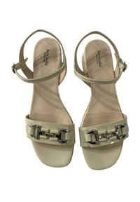 Sandali in pelle verniciata beige con cinturino alla caviglia, decorati con hardware e una superficie liscia e lucida. Marchio visibile sulla soletta.