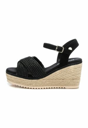 Sandalo con tacco a cuneo nero con parte superiore intrecciata, cinturino alla caviglia regolabile e piattaforma in sisal texturizzato. La suola liscia migliora comfort e stabilità.