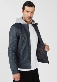 Herren navy Lederjacke mit grauem Hoodie, Reißverschluss vorne, Seitentaschen und einem gemusterten Futter. Verfügt über eine taillierte Passform und eine glatte Textur.