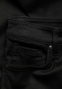 Mustat farkut, joissa on etutasku hienovaraisella ommella, metallinappi ja sileä pinta.