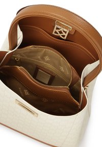 Jäsennelty käsilaukku, jossa on kerma-valkoinen ulkopinta teksturoidulla kuviolla, ruskeat nahkaosat, kultaiset metalliosat ja useita sisäosia.