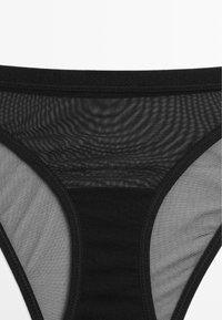 Sort mesh-thong med en glat talje og gennemsigtige sidepaneler, der viser et let, åndbart stof med en subtil tekstur.