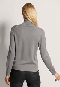 Grauer Strickpullover mit hohem Kragen, langen Ärmeln und gerippten Bündchen und Saum. Hergestellt aus einem weichen, strukturierten Stoff.