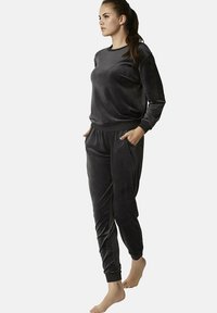 Zwart velours loungewear set met een langemouwtopp met geribde manchetten en bijpassende taps toelopende broek met zakken, gladde textuur.