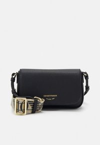 Borsa a tracolla in pelle nera con superficie texturizzata, caratterizzata da un logo dorato e una tracolla in tessuto decorata con motivo e dettagli a fibbia.