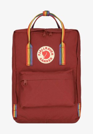 Sac à dos en tissu synthétique rouge de forme rectangulaire, avec des bretelles de couleur arc-en-ciel et une poche avant. Possède un logo circulaire au centre.