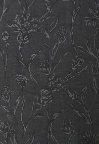 Tissu noir texturé avec un motif floral gris, comprenant des fleurs et des feuilles stylisées entrelacées. Surface lisse avec un léger éclat.