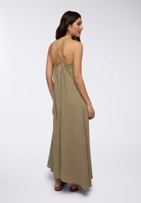 Abito maxi verde oliva con sottili spalline incrociate, design con schiena arricciata, tessuto fluente e vestibilità rilassata che arriva fino alla caviglia.