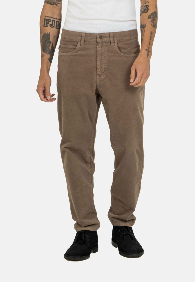 Brown corduroy pants with a straight-leg cut, five-pocket design, and a subtle texture. Worn with black ankle boots.