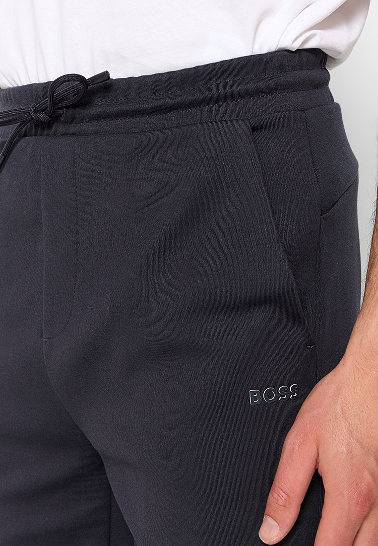 Pantalons de jogging noirs en tissu texturé, dotés de poches latérales et d'une taille élastique avec cordon de serrage. Logo BOSS en argent sur la jambe.
