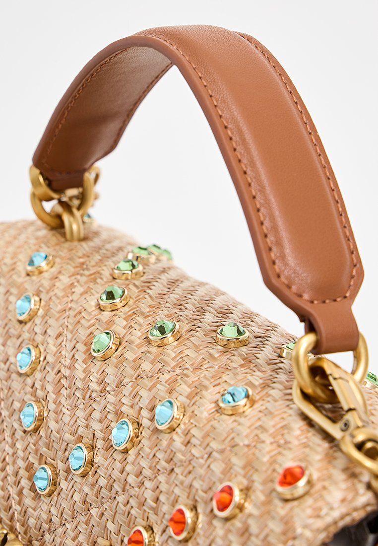 Bolso de paja tejido decorado con piedras preciosas verdes, azules y naranjas, que cuenta con un asa de cuero marrón acolchada con herrajes dorados.