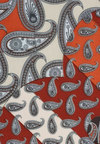 Patterned fabric with paisley motifs in black and white on alternating orange, cream, and rust colored geometric shapes.