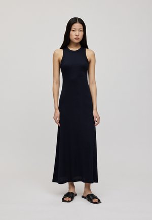 Marineblaues ärmelloses Maxikleid mit angepasstem Oberteil, glatter Textur und langem, fließendem Rock. Kombiniert mit schwarzen flachen Sandalen.