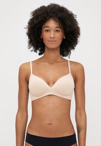 Beige polstret underwire BH med en glatt tekstur, dyp utringning, justerbare stropper og moderat dekning.