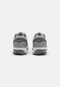 Pilki ir šviesiai pilki sportiniai bateliai, pagaminti iš tinklinės ir sintetinės medžiagos, su tekstūruotu kulnu ir itin akcentuota guma. Nike logotipas ant kulno.
