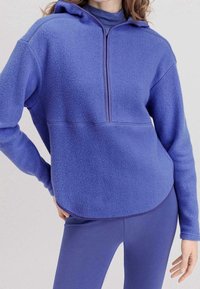 Lila fleece-pullover med halvdragkedja, huva och ribbad detalj, med en avslappnad passform och texturerad tyg för värme.