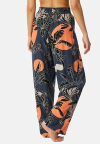 Pantaloni a fantasia floreale in blu navy con accenti arancioni e beige chiaro. Presentano una vita arricciata e un design ampio e svasato.