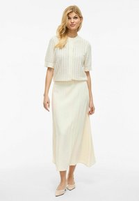 Cardigan texturé écru à manches courtes et col rond, assorti d'une jupe fluide à longueur de cheville.