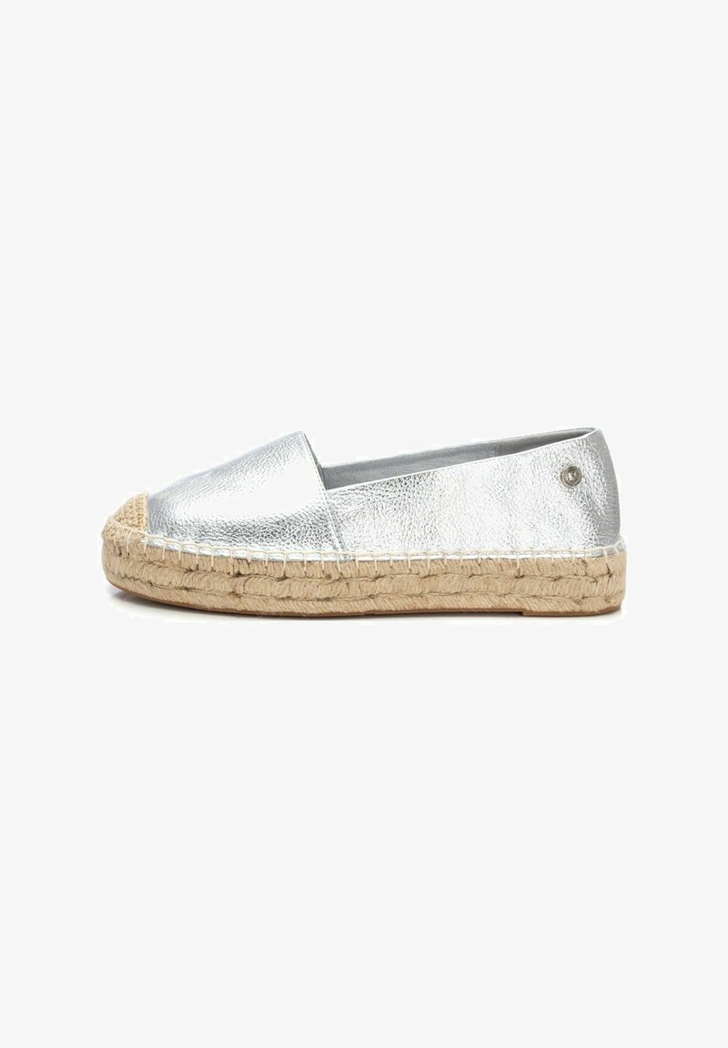 Espadrille plateado metálico con punta redonda, suela de cuerda de yute y tacón plano. Presenta detalles de costura y un pequeño acento metálico.