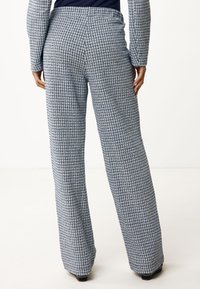 Blauw-witte geruite wijde broek met een soepele textuur en een hoge taille. Ontworpen met subtiele lijnen en een relaxte pasvorm.