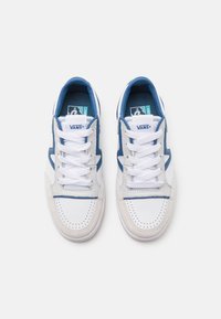 Paire de baskets Vans blanches et bleues avec des lacets blancs, des boîtes à orteils perforées et des étiquettes de langue marquées sur un fond blanc.