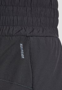 Melni sporta šorti ar elastīgu jostasvietu, ar šūtu vīli un "AEROREADY" logotipu gaiši pelēkā krāsā. Gluda, viegla auduma.