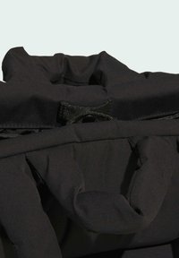 Black backpack with soft, textured fabric. Features a rolled top, adjustable straps, and a snap closure for security.