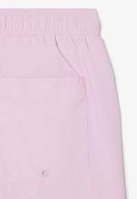 Shorts rose clair avec une taille élastique et une grande poche arrière équipée d'une petite fermeture à bouton.