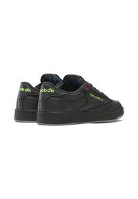 Black leather sneakers featuring a low-top design, textured surface, green and pink accents, and a thick rubber sole with Reebok branding.