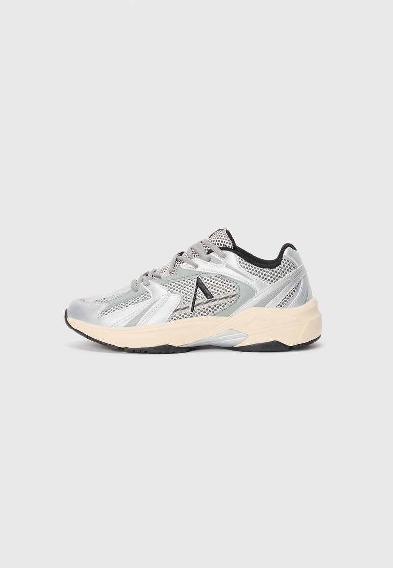 Zapatillas deportivas plateadas y grises con paneles de malla, acentos texturizados, diseño con cordones y una suela de goma beige. Presenta un logo sutil en el lateral.