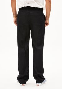 Zwarte losvallende broek met een elastische tailleband, twee achterzakken en een gladde textuur. Kenmerkt zich door een recht model.