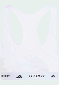 Hvit sports-BH med mesh tekstur og racerback-design. Har en svart "TECHFIT" logo og tre-stripes merkevare på det elastiske båndet.