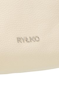 Krémovo sfarbená textúrovaná koža s jemným zrnom. Strieborné logo "RYŁKO" vytlačené na povrchu, ukazujúce rafinované remeselné spracovanie.