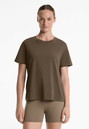 Bruine katoenen t-shirt met korte mouwen, ronde hals, comfortabele pasvorm, gladde textuur. Gecombineerd met bijpassende strakke shorts.